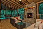 Covered porch with outdoor fireplace and dining area looking to the river